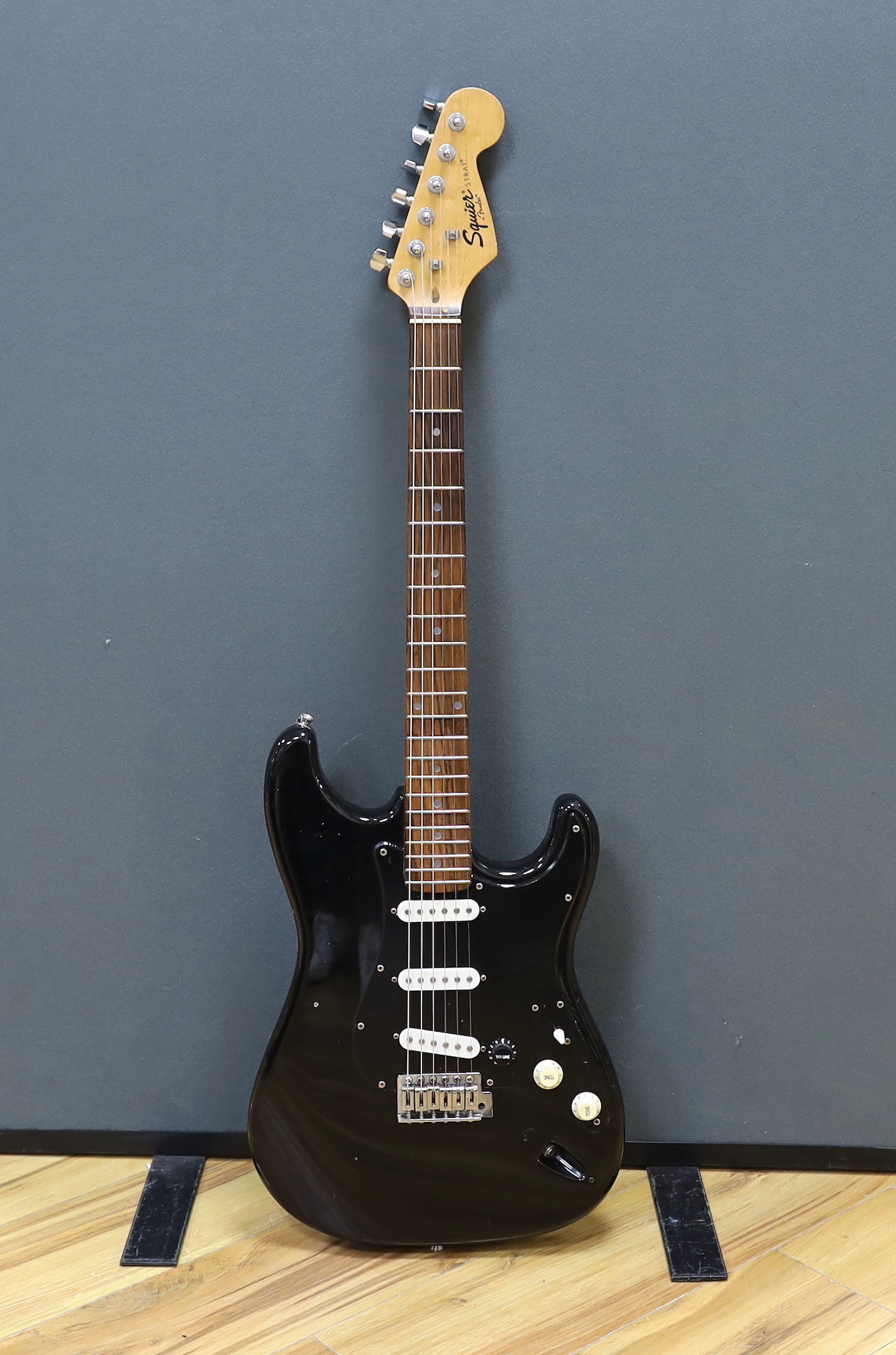 A cased Squier Strat by Fender electric guitar with rosewood neck and balance lacquer body, together with a Harris Tweed flight case
